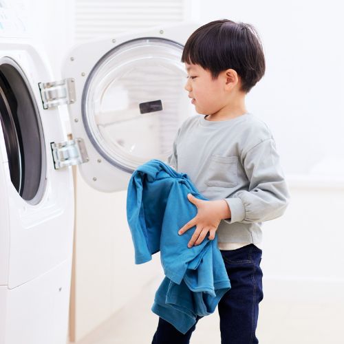 Young boy putting clothes in the washing machine