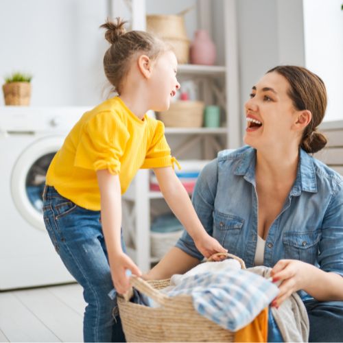 Mom and daughter laughing while doing laundry together